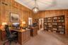 Virtually staged home office showcasing the built-in shelving, generous workspace, and potential for multiple workstations.