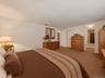 Virtually staged primary bedroom highlighting the generous room size, storage, and convenient connection to the adjoining bathroom.
