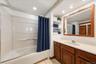 Full bathroom featuring a tub/shower combination, spacious vanity, built-in shelving, and generous mirror space.