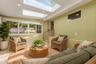 Virtually staged sunroom showcasing the abundant natural light, skylights, and flexible seating possibilities.