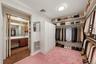Virtually organized walk-in closet highlighting the extensive hanging space, shelving, and convenient bathroom access.