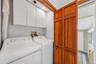 Convenient laundry area with side-by-side washer and dryer, overhead cabinetry, and additional storage.
