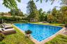 Virtually staged pool area showcasing lounge seating, outdoor dining, and the property’s private landscaped setting