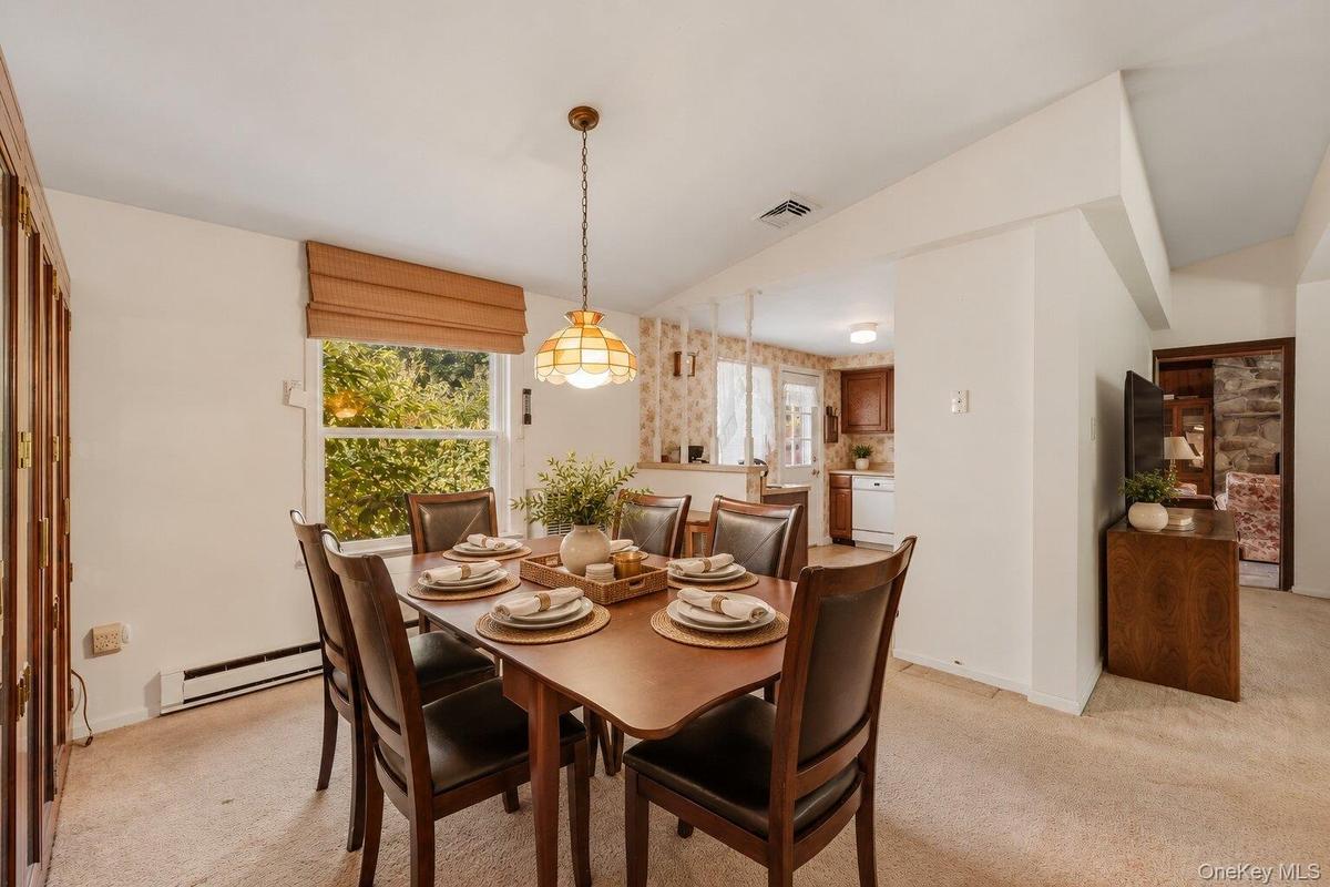 Virtually Staged. Bright dining area with a large window, comfortable seating space, and direct access to the nearby kitchen.