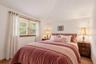 Virtually staged bedroom showcasing the room’s airy ceiling height, large window, and furniture placement potential.
