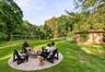 Virtually staged backyard showcasing a fire pit seating area, volleyball space, and the property’s generous lawn.