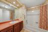 Functional full bath with generous counter space, wood cabinetry, and a tub/shower combination.
