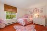 Virtually staged bedroom demonstrating a cheerful child-friendly layout while highlighting the room’s size and large window.