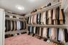Virtually organized walk-in closet showcasing the generous storage capacity, multiple hanging sections, and abundant shelving.