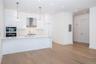 Kitchen featuring light hardwood / wood-style floors, wall chimney exhaust hood, decorative light fixtures, double oven, and white cabinets