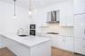 Kitchen featuring white gas stovetop, white cabinets, wall chimney exhaust hood, sink, and pendant lighting