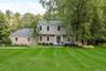 Two-story colonial residence with light tan siding, a dark gray shingle roof, and white-framed windows
