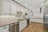 Elegant white kitchen w/ pantry, granite countertops, & custom cabinetry.