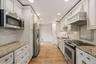 Elegant white kitchen w/ pantry, granite countertops, & custom cabinetry.