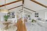 Virtually staged open-plan great room w/ hardwood floors, exposed wood beams, and fresh paint.