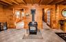Wood paneling throughout, exposed wood beam ceiling, central wood-burning stove, and two frosted glass French doors