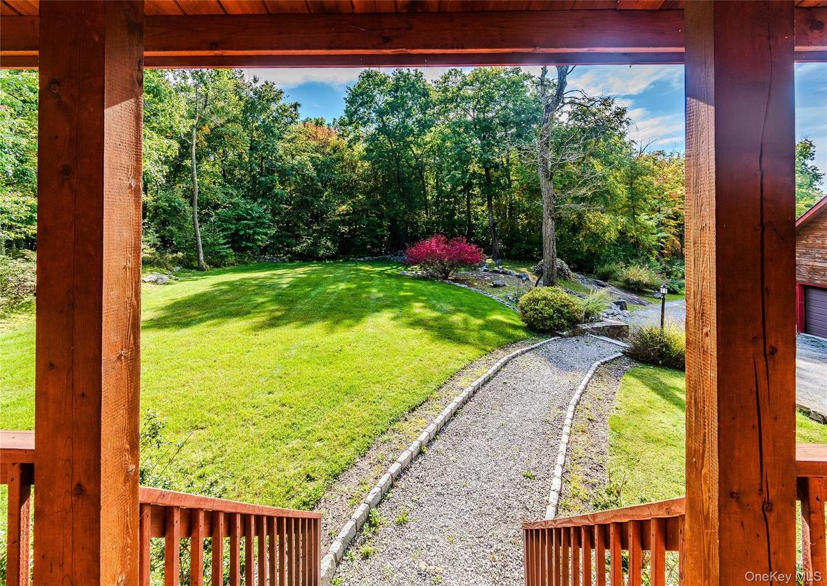 Expansive outdoor grounds featuring a gravel pathway, mature trees, and a vibrant red-leafed shrub