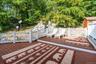 Multi-level outdoor deck with composite decking and white railing, surrounded by natural rock formations and mature trees