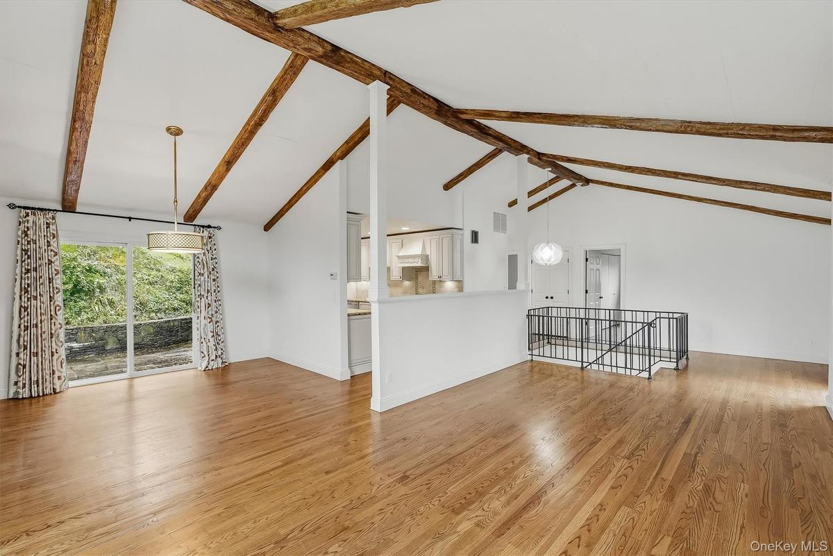 Open-plan great room w/ hardwood floors, exposed wood beams, and fresh paint.