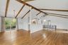 Open-plan great room w/ hardwood floors, exposed wood beams, and fresh paint.