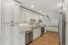 Elegant white kitchen w/ pantry, granite countertops, & custom cabinetry.