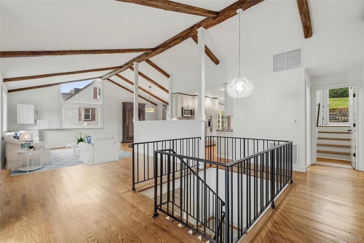 Open-plan great room w/ hardwood floors, exposed wood beams, and fresh paint.