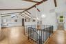 Open-plan great room w/ hardwood floors, exposed wood beams, and fresh paint.