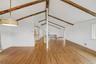 Open-plan great room w/ hardwood floors, exposed wood beams, and fresh paint.