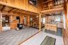 Wood-paneled interior featuring a wood-burning stove, exposed wood beam ceiling, and a kitchen with wood cabinetry