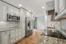 Elegant white kitchen w/ pantry, granite countertops, & custom cabinetry.