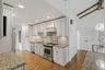 Elegant white kitchen w/ pantry, granite countertops, & custom cabinetry.