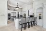 Gourmet kitchen with stainless steel appliances, white cabinetry, granite countertops, a large island with seating, and recessed lighting