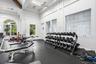 Fitness facility with high vaulted ceilings, architectural wall paneling, large arched windows, and rubberized flooring