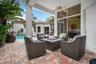 Covered outdoor patio with a ceiling fan, paver flooring, expansive glass sliding doors