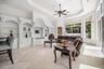 Built-in white cabinetry with arched details, tray ceiling with recessed lighting, ceiling fan, large windows, and marble flooring