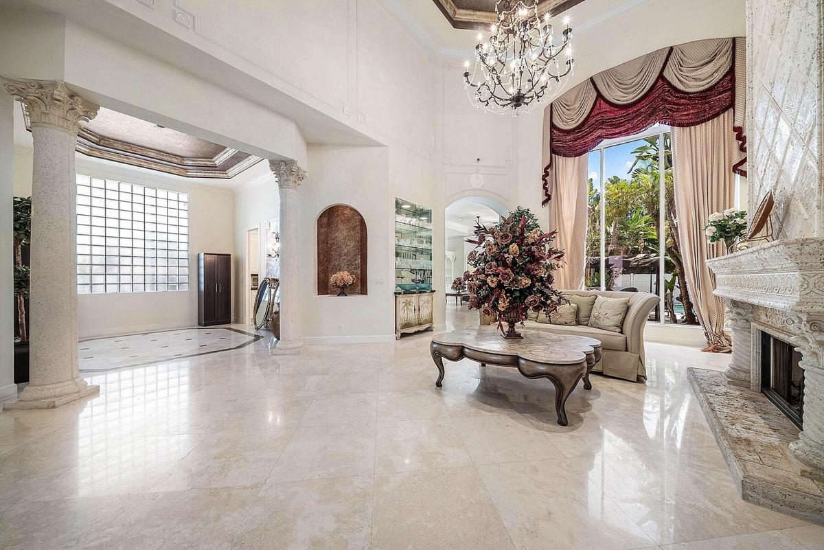 Soaring ceilings, polished marble flooring, stone fireplace, decorative columns.