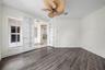Wood-finish flooring, crown molding, double French doors, large window, and ceiling fan