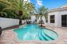 Freeform swimming pool with a stone coping, integrated waterfall feature, and built-in steps
