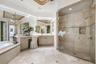 Vanity with ample counter space, integrated makeup area, and large mirrored wall