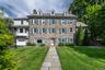Stone facade residence with multiple dormer windows, a prominent walkway, and an attached two-car garage