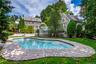 Curved swimming pool with integrated steps, surrounded by stone coping and a manicured lawn