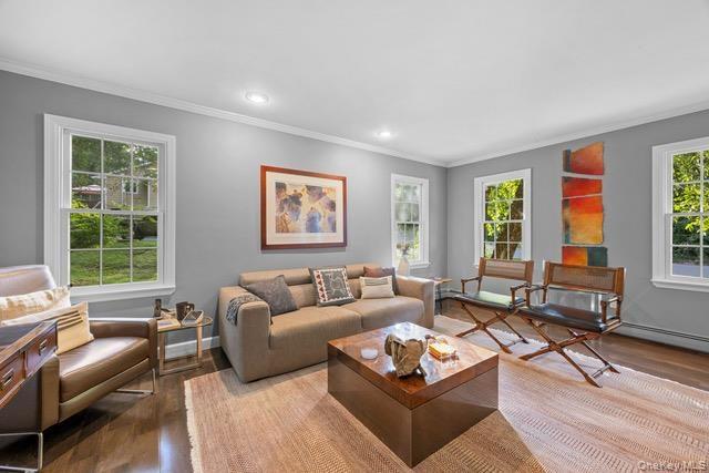 Wood flooring, recessed lighting, crown molding, and multiple windows with white trim