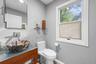 Vessel sink with a unique stone basin, wall-mounted faucet, wood-finish vanity, and a large window