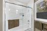 Tub-shower combination featuring subway tile surround, glass sliding door, and integrated shower niche