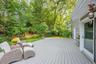 Expansive deck with slatted surface, bordered by a lush, green landscape and mature trees