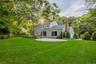 Spacious backyard featuring a manicured lawn, mature trees, a paver patio, and a brick chimney