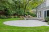 Expansive lawn with a circular paver patio, composite deck, and mature landscaping
