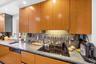 Wood-finish cabinetry paired with a built-in cooktop, undermount sink, and recessed lighting