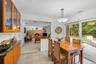 Kitchen and dining area looking into family room featuring tile flooring, glass-front cabinetry, and granite-finish countertops