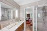Bathroom featuring a frameless glass-enclosed shower, wall-mounted shower fixture, an integrated rectangular sink, wood-finish cabinetry, and a large 